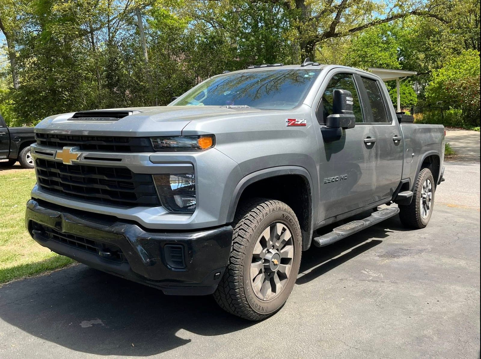 Freshly detailed gray Chevrolet Silverado HD Z71 in a tree-shaded driveway after an exterior detail by ShineCraft in Olathe.